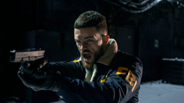 istock Shouting FBI agent with a gun aiming somewhere on a dark street 1465023626