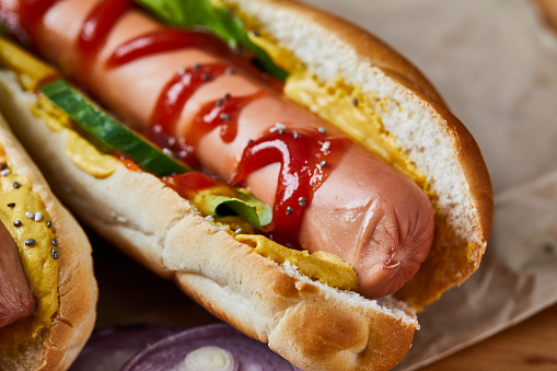 Two tasty hotdogs served on a recyclable paper, on a wooden home, bar or restaurant table, a close up image with a copy space