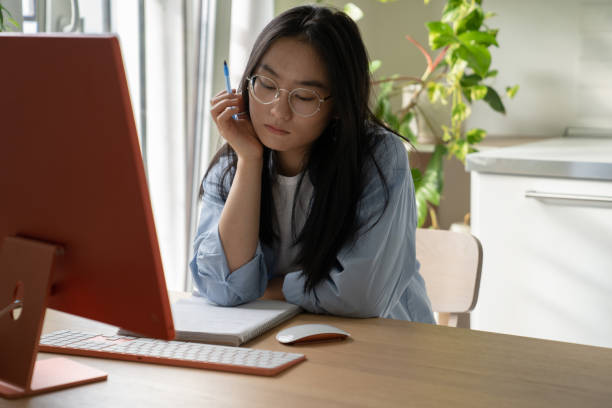 istock Tired bored Asian woman student falls asleep sits at computer in home interior during e-education 1465028410