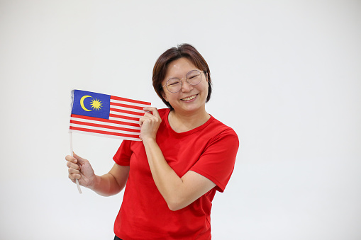 An Asian woman is holding Malaysian national flag joyfully