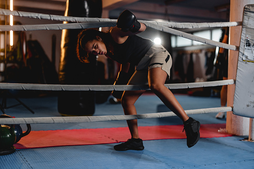 Beautiful Hispanic female boxer in a gym. Entering a boxing ring for a sparing match.