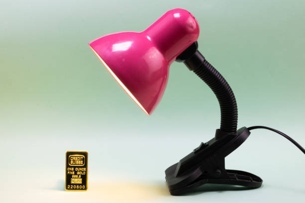istock Desk lamp illuminating small gold ingot 1465034670