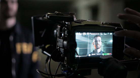 Professional camera screen, shooting a scene with an FBI agent, we see his face on a screen in close-up. FBI agent backstage shooting
