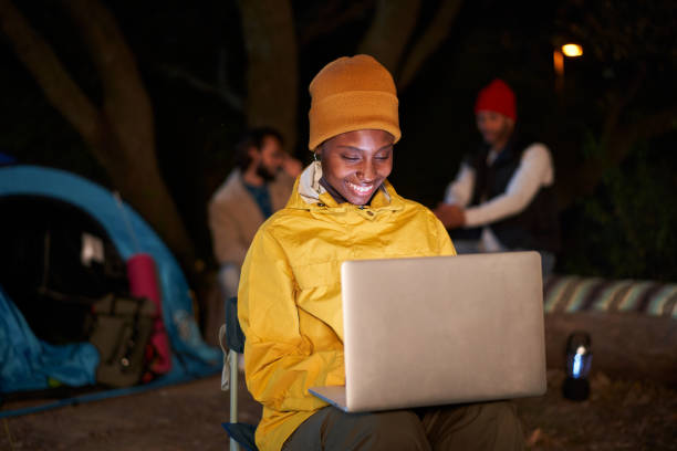 istock Workaholic young African girl sitting using her computer, smiling and camping winter at night. 1465038856