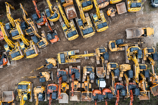 Selby, UK - February 11, 2023.  Aerial view directly above an industrial machinery plant hire with diggers and bulldozers parked together in an industry background with copy space