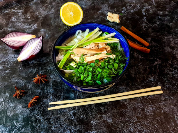 Traditional Pho Bo soup with beef, rice noodles, ginger, lemon in a bowl on a dark background. Vietnamese and Asian cuisine.