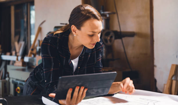istock Caucasian female carpenter Looking at Blueprints 1465064534