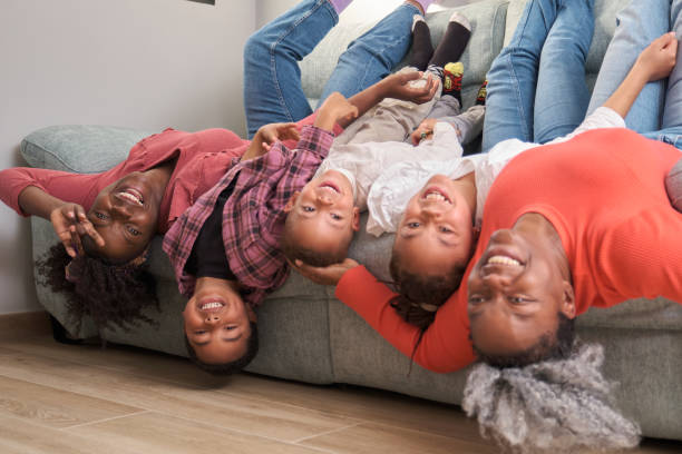 glückliche afrikanische familienbindung und gemeinsames genießen auf dem sofa. - women group of people lying down mother stock-fotos und bilder