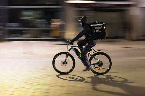 Lille, France - October 02, 2022: unidentified man delivering food on a bike for Uber Eats, that is an online food ordering and delivery platform launched by Uber in 2014 across 45 countries