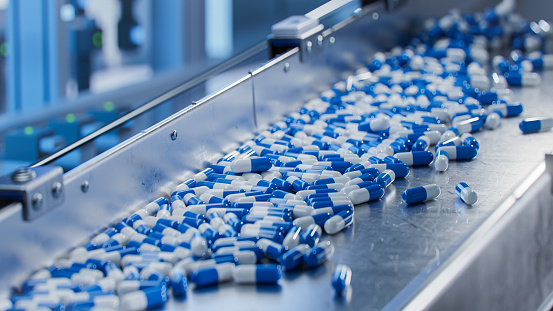 Cápsulas azules en transportador en fábrica farmacéutica moderna. Proceso de fabricación de tabletas y cápsulas. Primer plano de la línea de producción de medicamentos médicos. photo