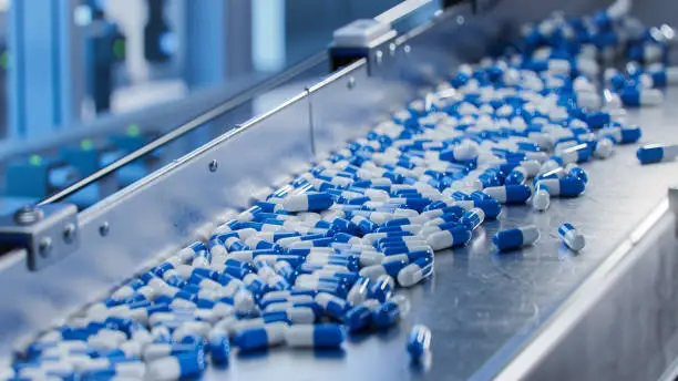 Photo of Blue Capsules on Conveyor at Modern Pharmaceutical Factory. Tablet and Capsule Manufacturing Process. Close-up Shot of Medical Drug Production Line.