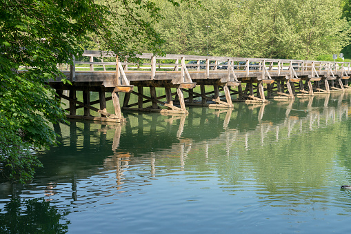 Long wooden bridge over the river Krka, forest in background.