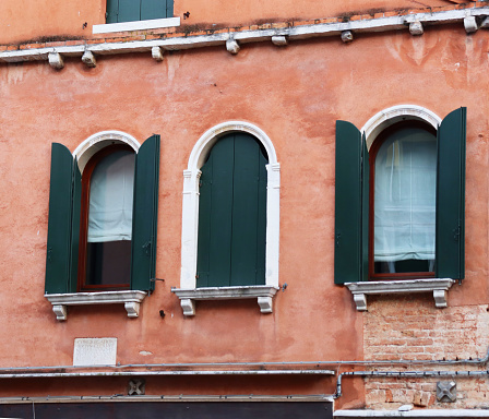 Front old red brick wall building with shutters window. European architecture. Vintage building in Venice, Italy. Venetian balcony