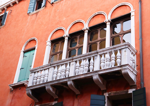Ancient balcony with arches and decoration in Italy concept photo. Venetian architecture. Red wall vintage building in Venice, Italy. Venetian balcony