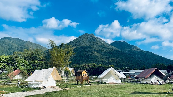 A beautiful camping site surrounded by mountain range with a blue cloudy sky background