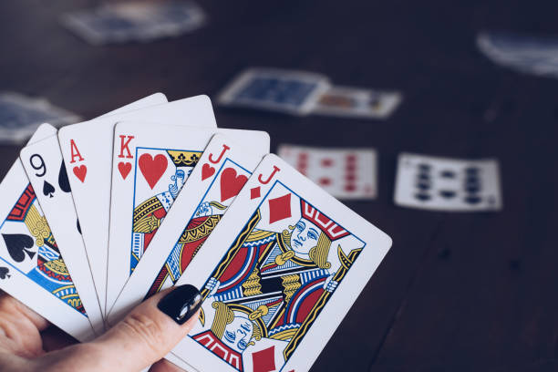 istock Womans hand holding playing cards at a table 1465081148