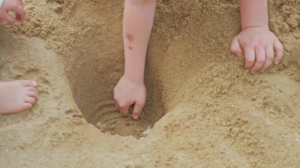 istock Caucasian Kids Having Fun Digging Hole in Sandbox Looking For Hidden Treasure 1465084341