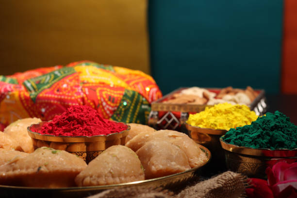 Abeer gulal a dry organic color powder with a traditional Indian sweet dish Gujiya pedukiya for the celebration of Holi a festival of colors celebrated in India during spring season stock photo