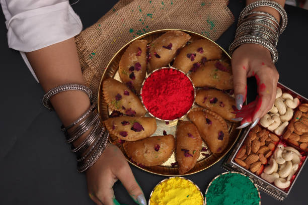 una mujer dama con hermosos brazaletes arreglando abeer gulal polvo de color seco y dulce indio gujiya pedukiya kashew para la celebración del festival de colores holi - gujia fotografías e imágenes de stock