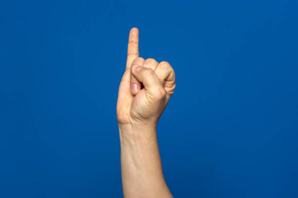 Man's hand with the little finger raised as a sign of promise or oath, isolated on blue background. Man's hand with the little finger raised as a sign of promise or oath, isolated on blue background pinky finger stock pictures, royalty-free photos & images