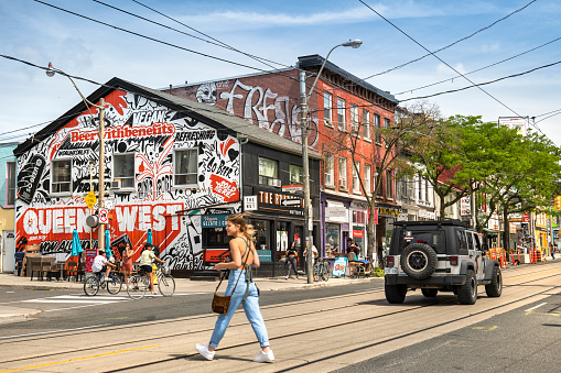 Toronto, Canada - August 16, 2021:  People walk and shop by the trendy businesses of the Queen Street West area in the urban downtown
