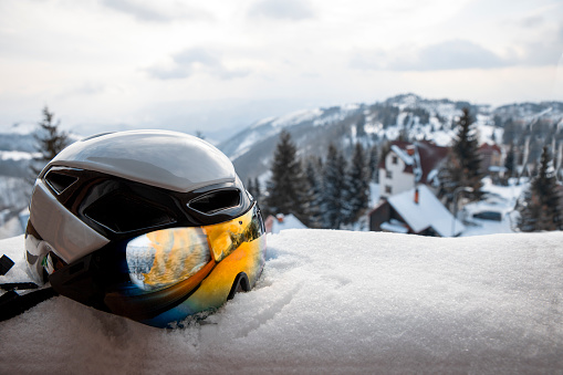 Ski helmet with reflective colors googles in snow with mountain hills in background. Copy space