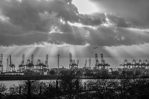 Panorama line of cranes and windmills and sunbeams through the clouds in Hamburg