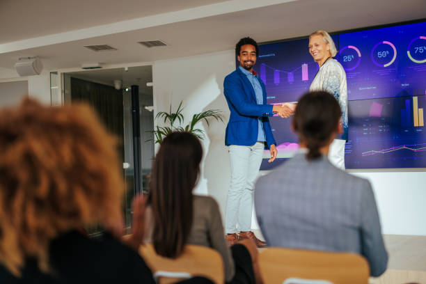 istock Joyful businesspeople are on stage in convention handshaking. 1465094829