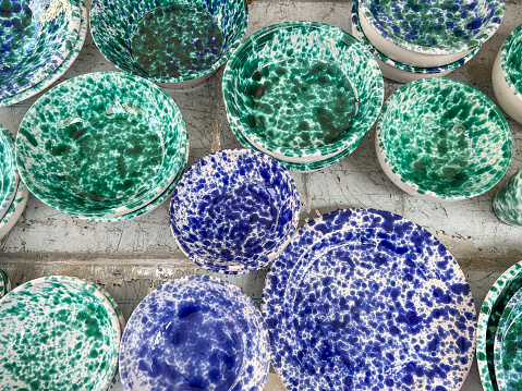ceramics, top view handmade blue and green colored ceramic or clay plates and bowls as a background. handmade blue and green porcelain or ceramic plates on table