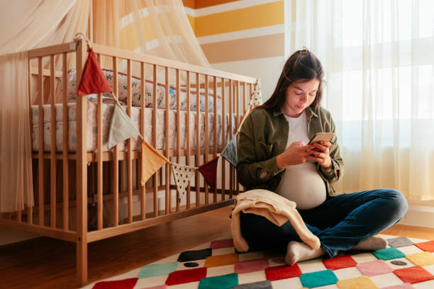 istock Pregnant woman using cellphone in nursery. 1465096243