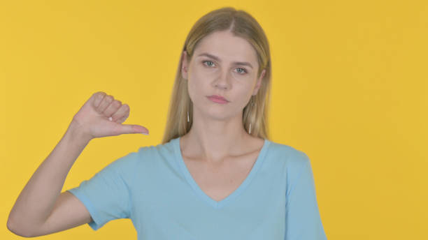 istock Thumbs Down by Young Woman on Yellow Background 1465098441