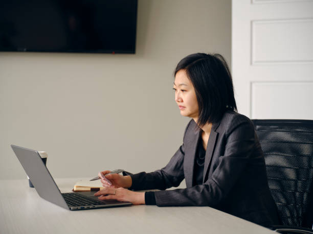 istock Woman in an Office Usuing a Laptop Computer and Smartphone 1465098820