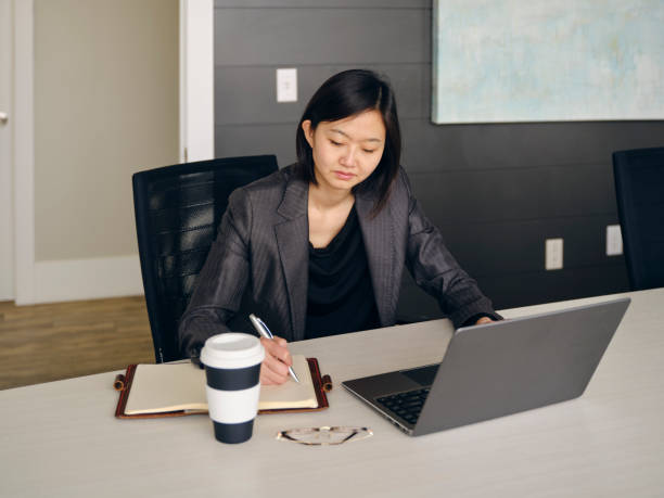 istock Woman in an Office Usuing a Laptop Computer and Smartphone 1465098836