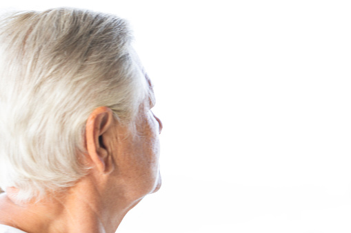 Side view of unrecognizable caucasian senior woman daydreaming  in front of  white background.