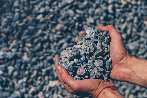 Crushed stones in the hands of a man. Selective focus. Nature.