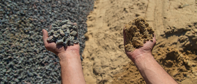 Sand and gravel in the hands of a man. Selective focus. Nature.