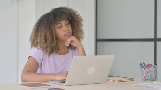 istock Young African Woman Thinking while Working on Laptop 1465114468