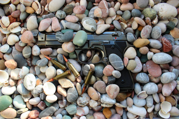Bullets Near Discarded Handgun In A Small Pebbles On Sea Shore