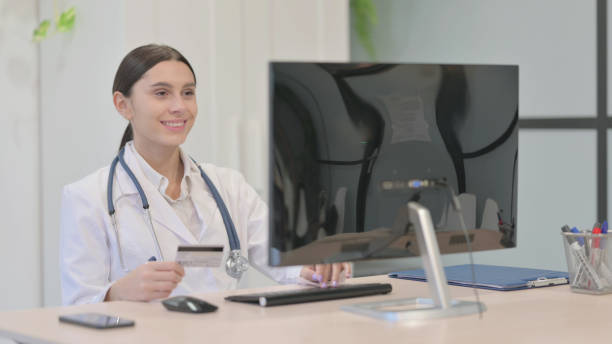 istock Young Female Doctor Shopping Online Payment on Desktop Computer 1465129979