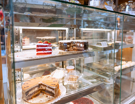 Assortment of freshly-made cakes and desserts sitting in a glass display counter in an artisanal bakery and cafe