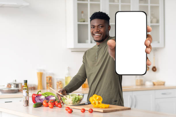 istock Dieting App. Smiling Young Black Man Holding Blank Smartphone In Kitchen 1465136687