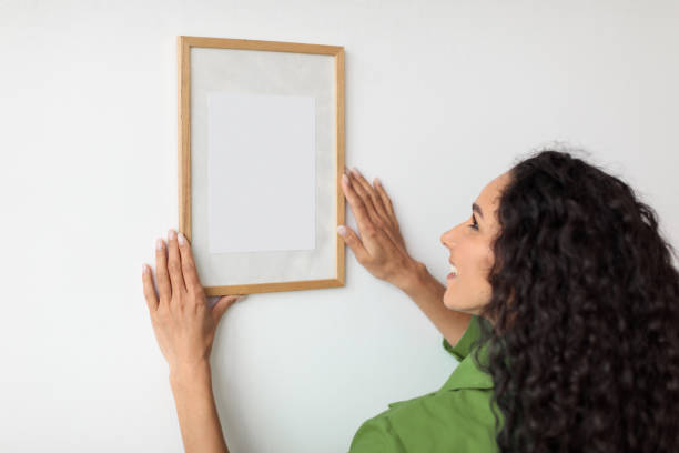 istock Female Hanging Blank Picture In Frame On Wall At Home 1465137878