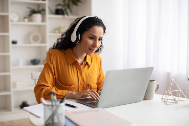 istock Female Freelancer Using Laptop Wearing Headphones Working Online In Office 1465137904