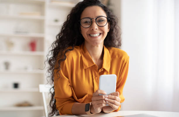 istock Cheerful Middle Eastern Woman Using Mobile Phone Posing Sitting Indoor 1465138156