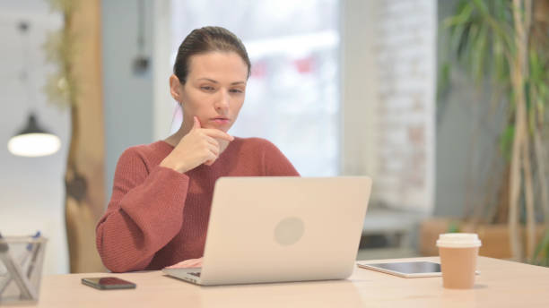 istock Beautiful Woman Thinking while Working on Laptop 1465140320