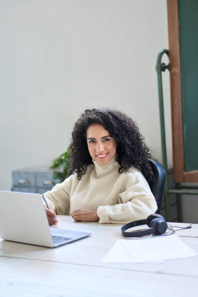 istock Young smiling female worker sitting at work desk with laptop. Vertical portrait 1465145785