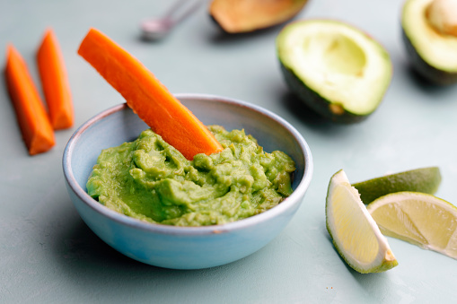 plate of corn tortilla chips with guacamole dip close up