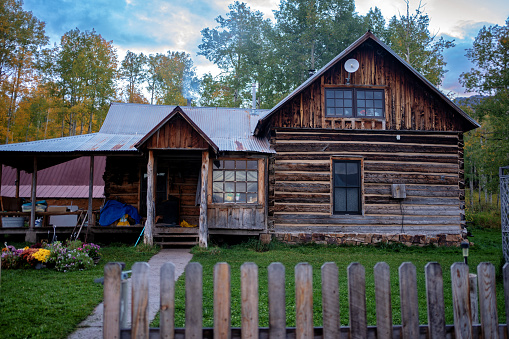 Rustic Log Cabin with Green Yard and Old Picket Fence in the Autumn in Southwestern Colorado Near Telluride at an Authentic Working Ranch Near Wilson Peak withAspen Trees in the Background