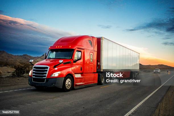 Brightly Red Colored Semitruck Speeding On A Twolane Highway With Cars In Background Under A Stunning Sunset In The American Southwest Stock Photo - Download Image Now