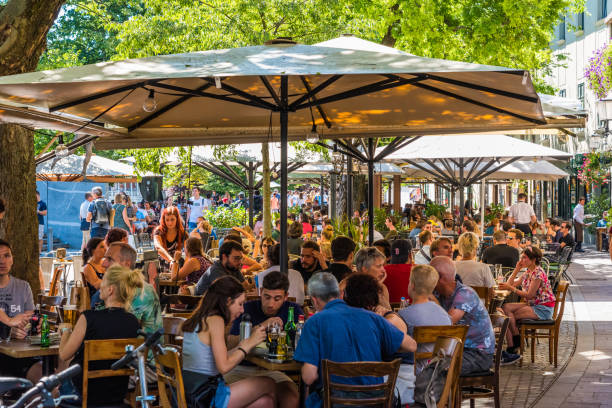 Crowded restaurants during the lunch hour in the central part of the city Ljubjana, Slovenia - 17 Aug, 2019 - People having lunch in packed restaurants during a hot day in the capital busy restaurant tables stock pictures, royalty-free photos & images